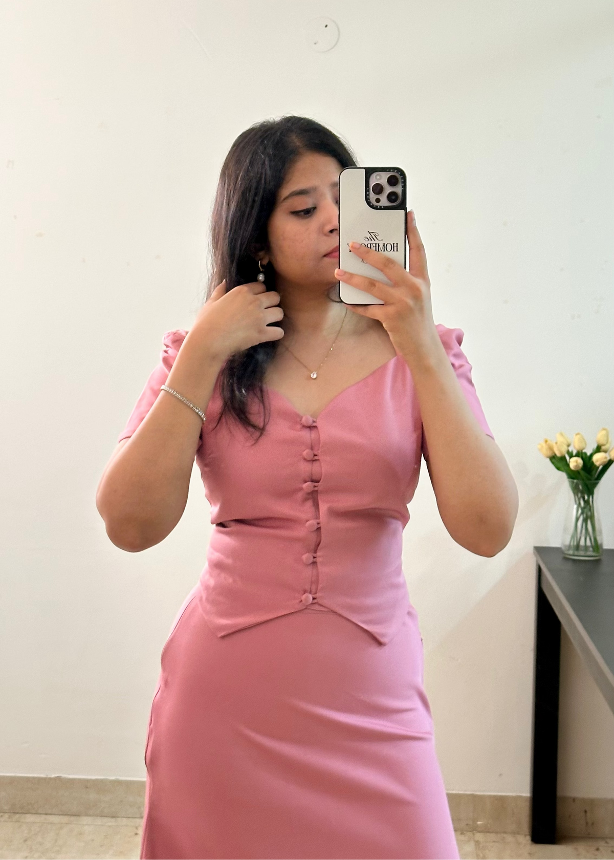 Woman taking a mirror selfie wearing a pink dress indoors.